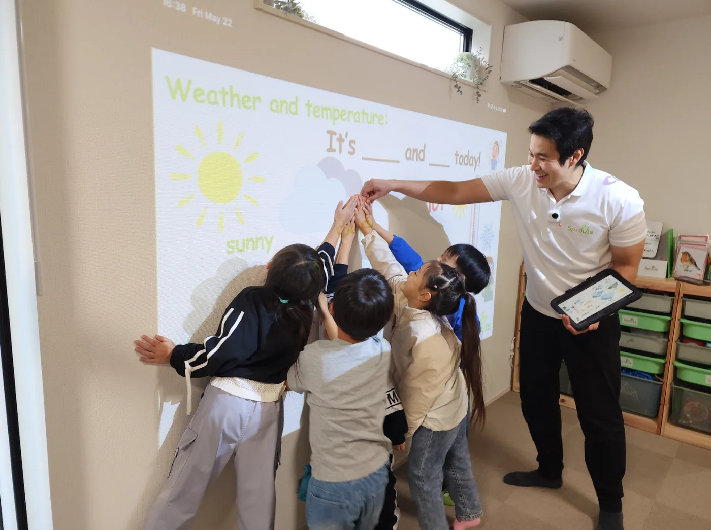草加市の英語教室で、子どもたちが先生と一緒に天気の英語表現を学んでいる様子