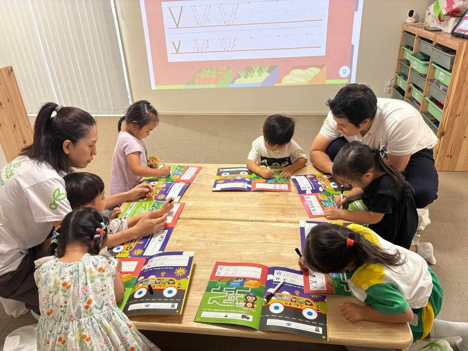 ワークブックとホワイトボードを使って英語の読み書きに取り組むSproutsの子どもたち
