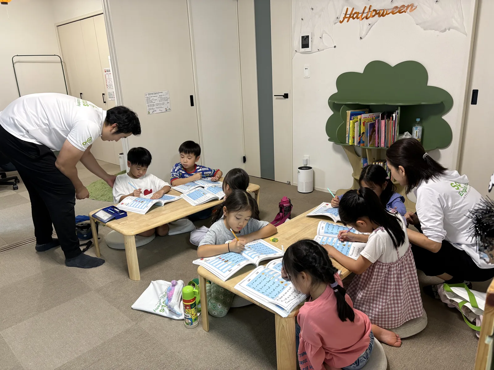 ワークブックに取り組む子どもたちを先生が近くでサポートするSproutsのレッスン