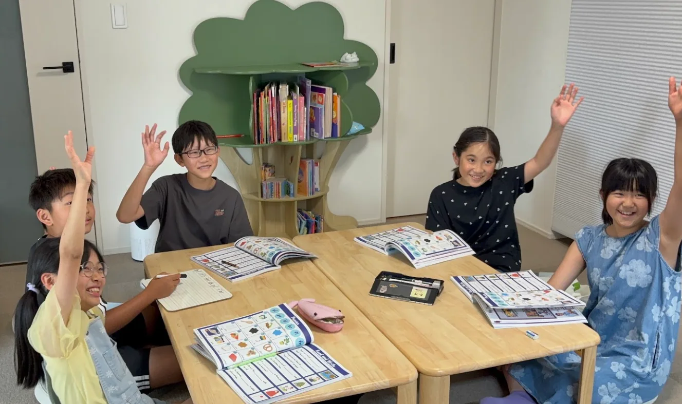 英語教材を開きながら手を挙げて参加するSproutsの小学生