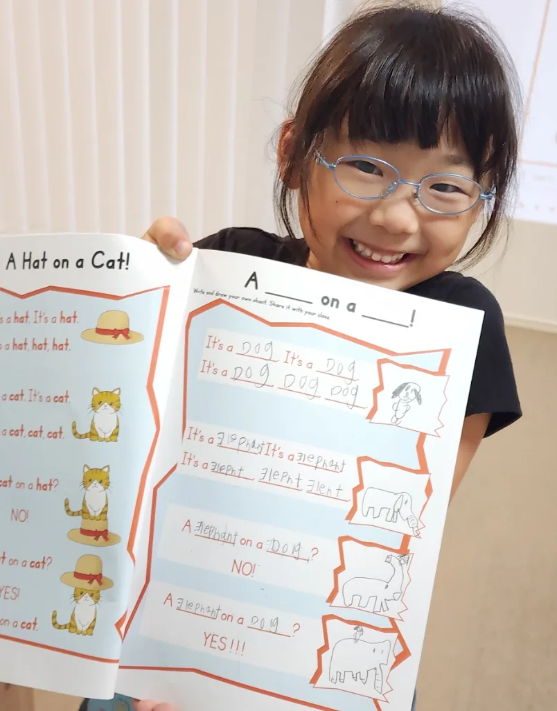 英語のワークブックで取り組んだ読み書きを見せる子ども